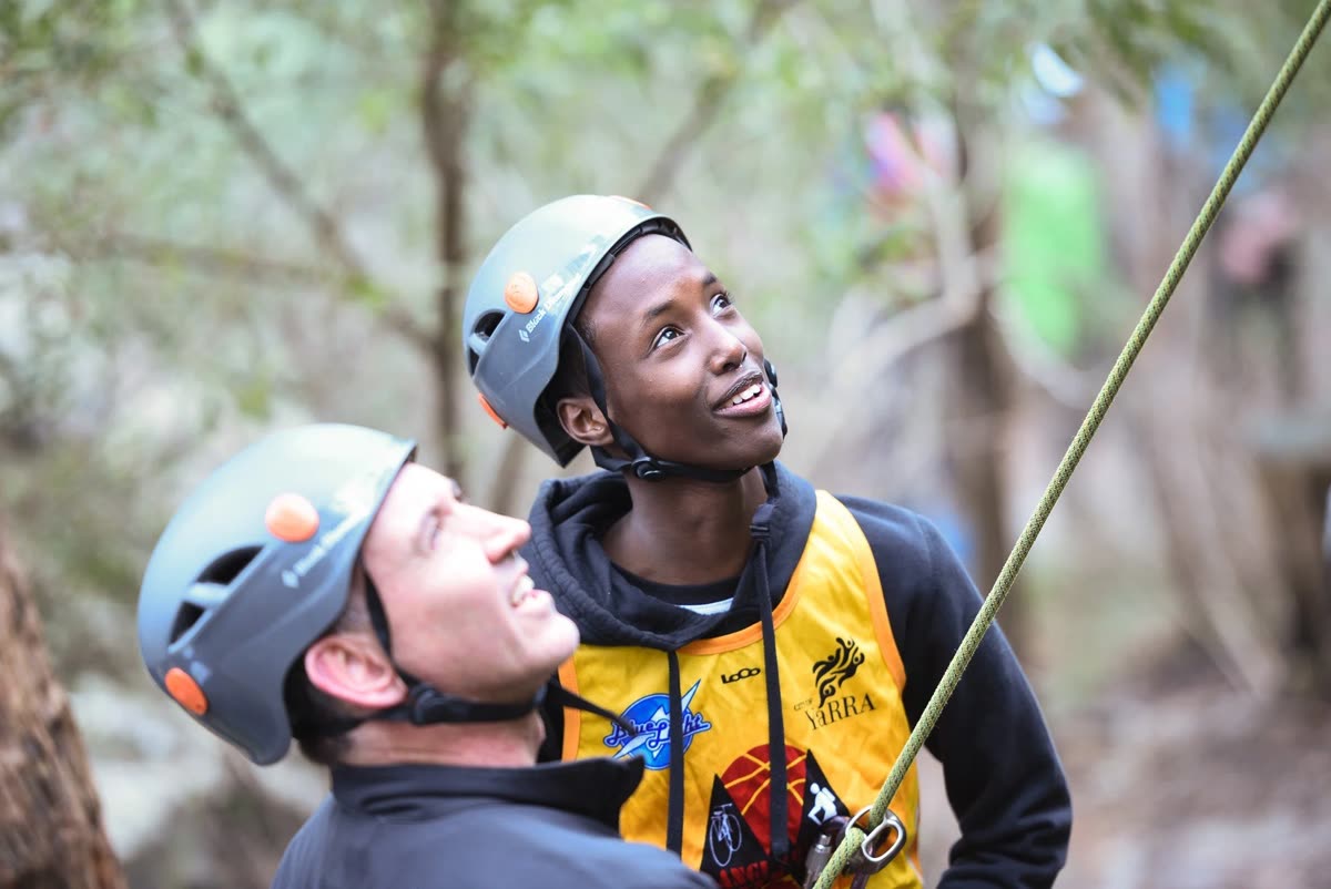 Two participants in climbing helmets during an abseiling activity
