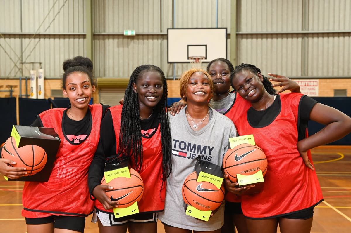 Players holding basketballs at an indoor court after a session