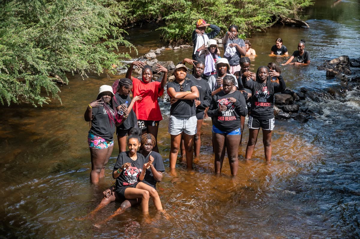 A large group standing together in a creek on a Home Ground Hub outdoor day