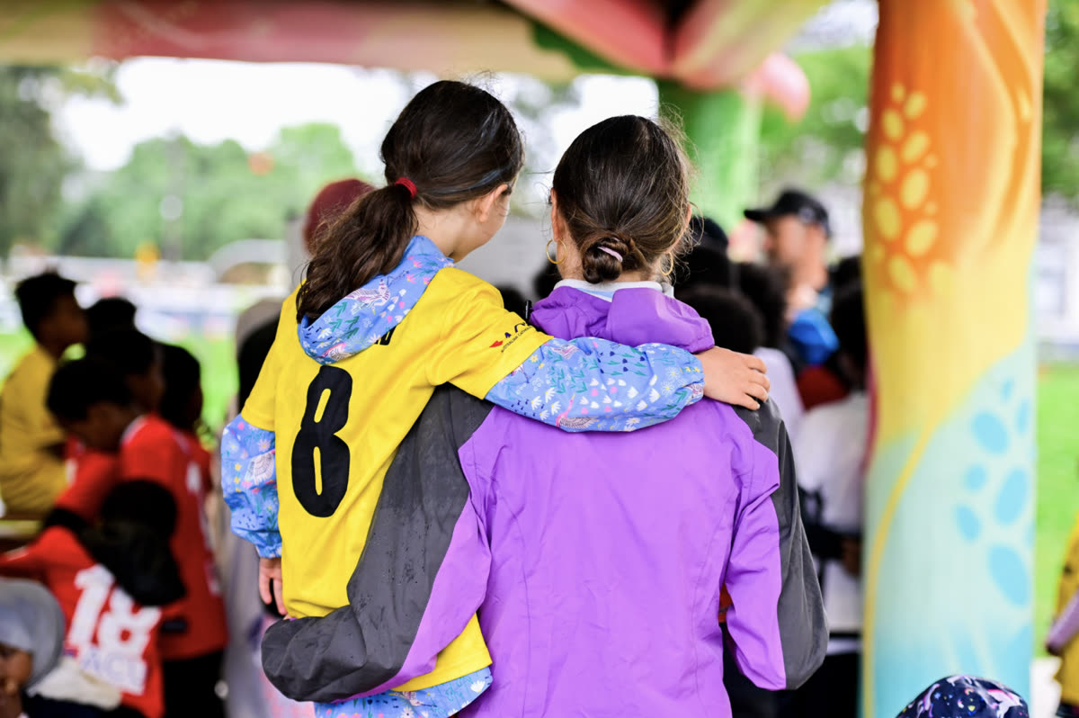 Two players in training bibs with their arms around each other at a Home Ground Hub session