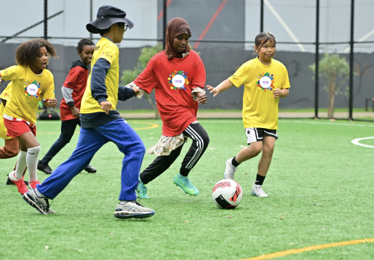 Young players chasing the ball across the pitch during a session